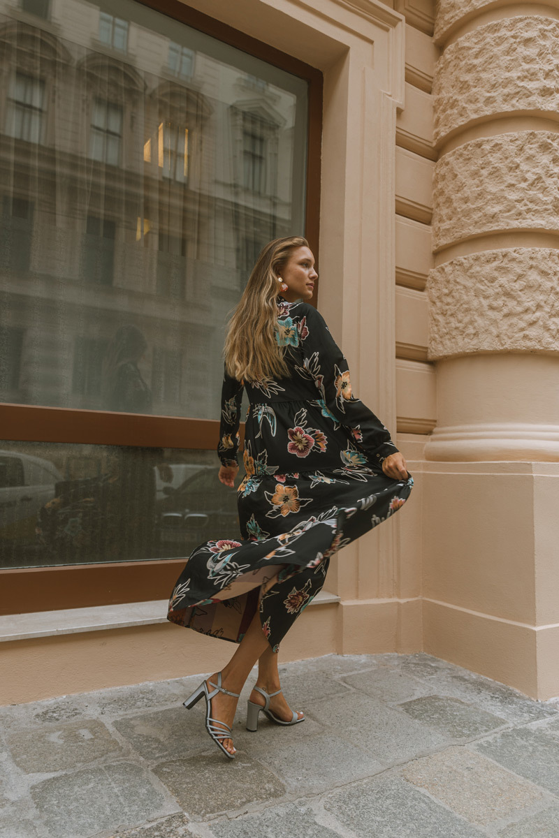 Blonde girl wearing a long dress, swirling in front of an historic building