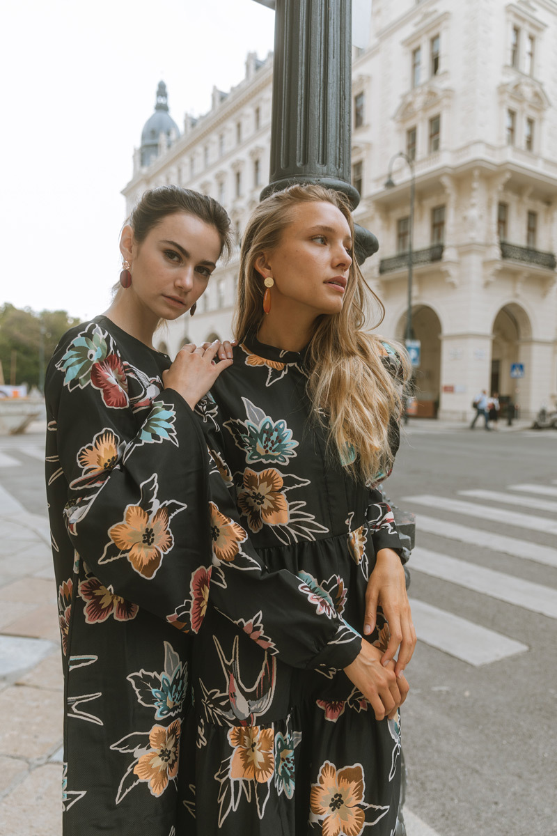 Two girls standing wearing dresses, standing in front of a street light