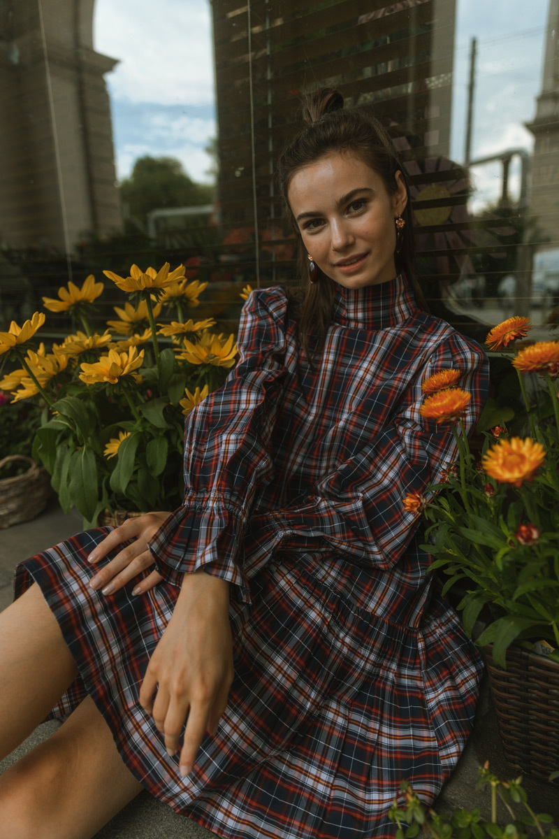 Girl sitting in between of flowers, wearing a dress