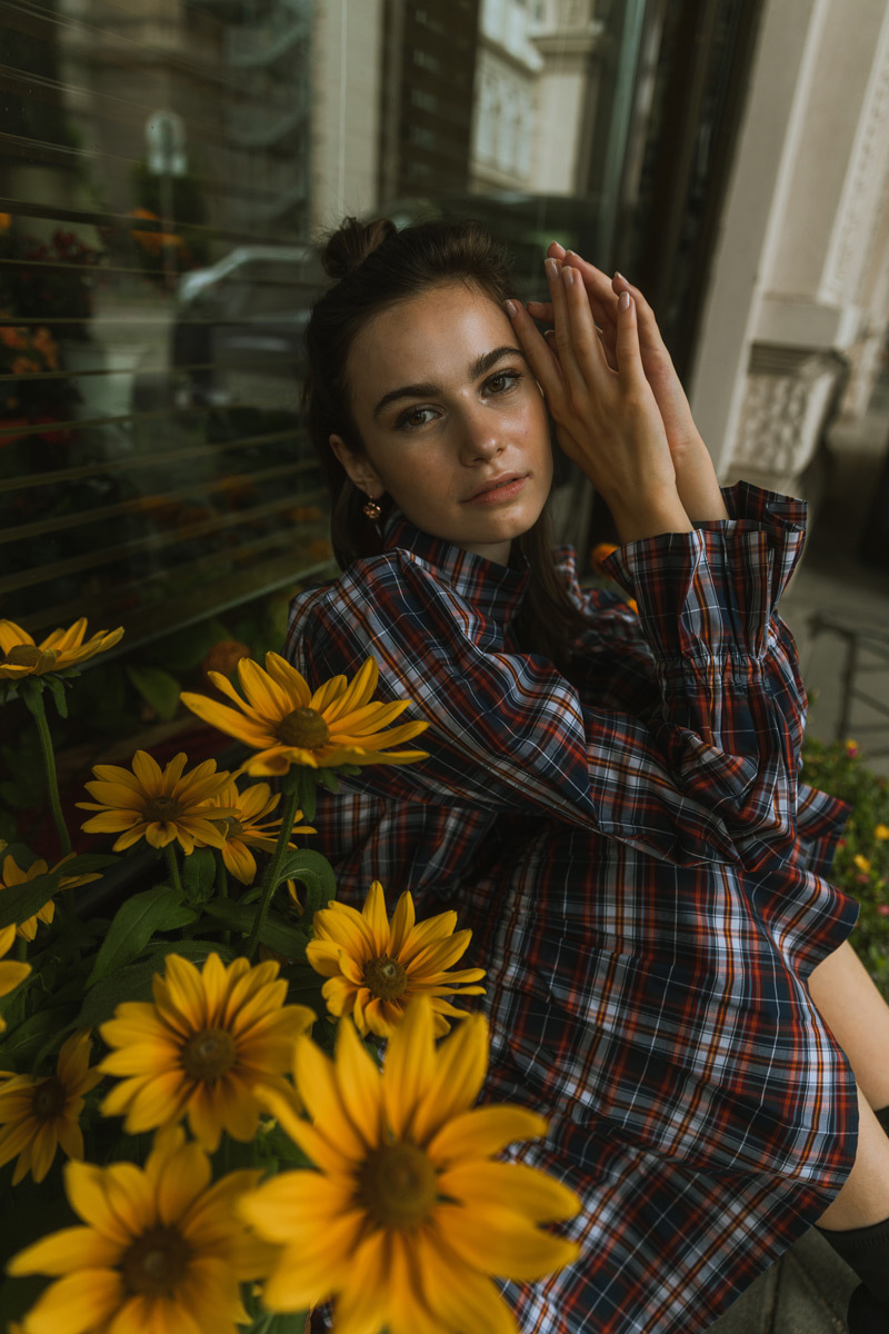 Girl sitting inbetween of flowers, wearing a dress