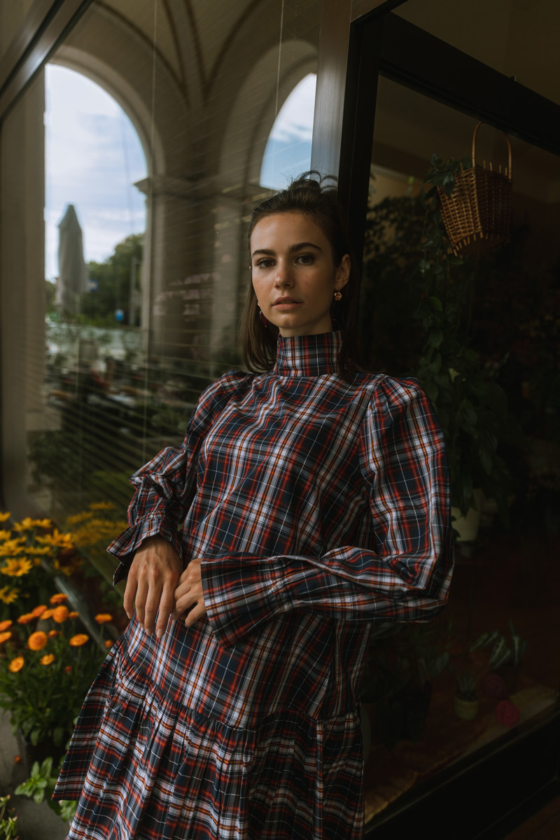 Girl leaning onto a door, wearing a dress