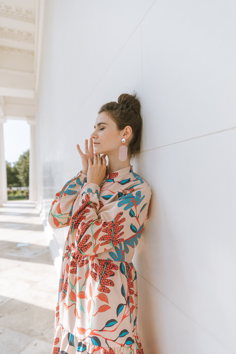 Girl in front of a white wall, leaning against the wall with the eyes closed