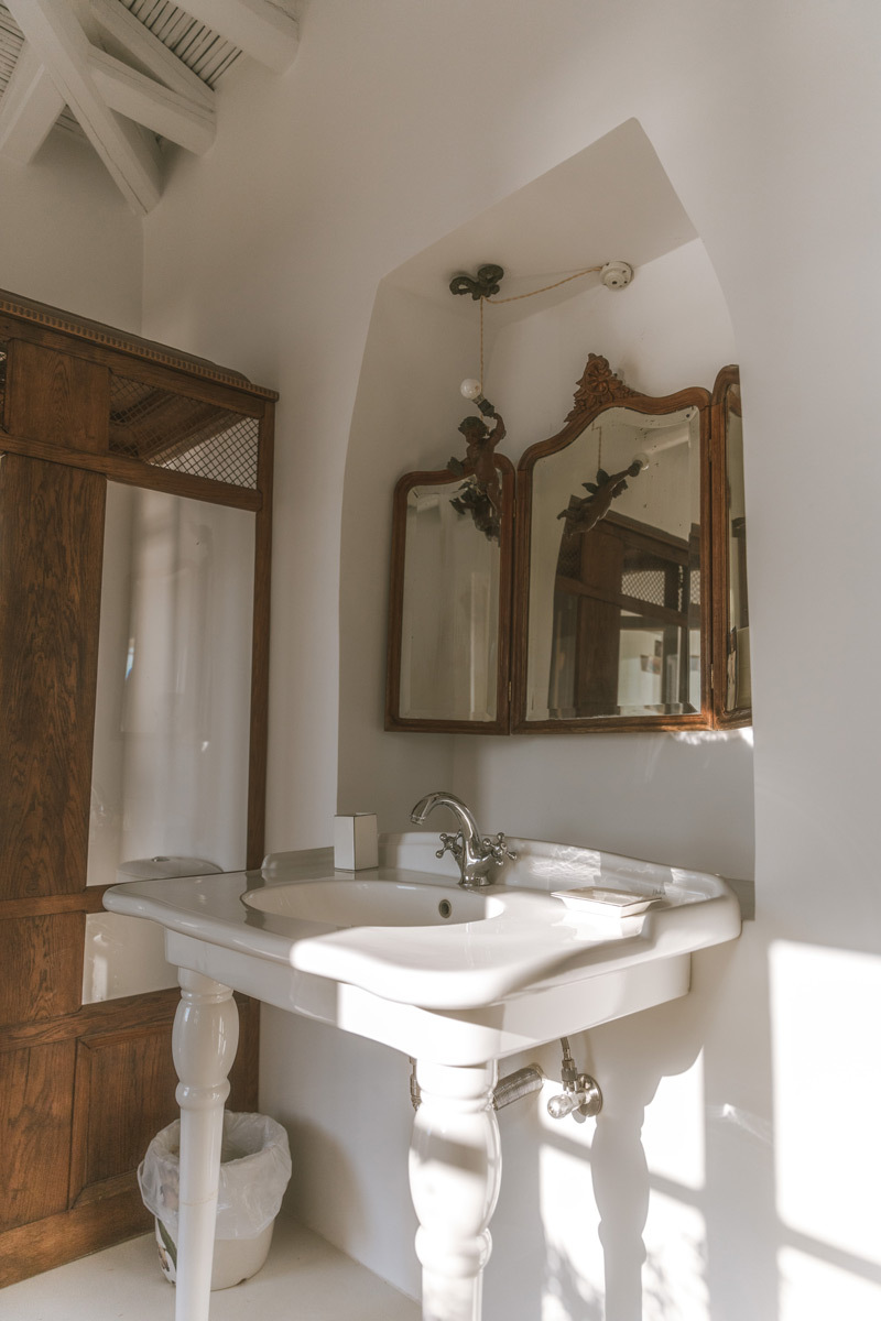 A white sink with a wooden mirror