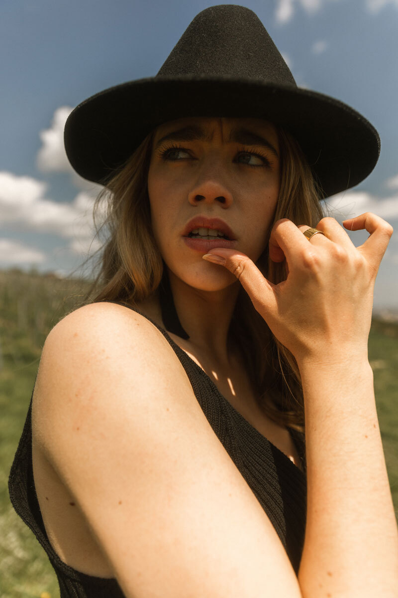 Blonde girl wearing a black hat and making a funny face