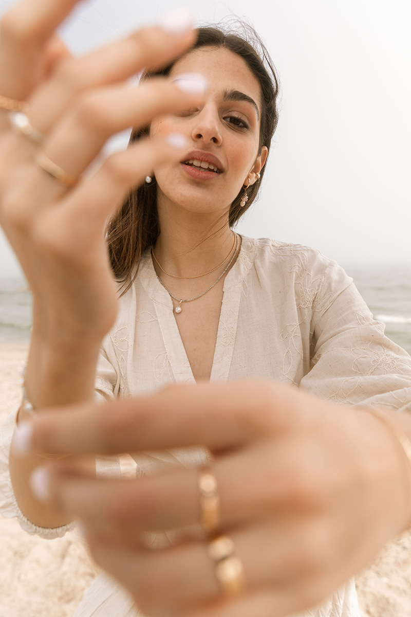 Girl standing on the beach with jewellery on her hands