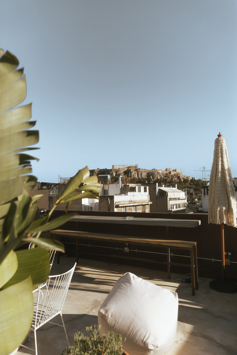 Terrace with palm trees, chairs and the view of the Acropolis in Athens