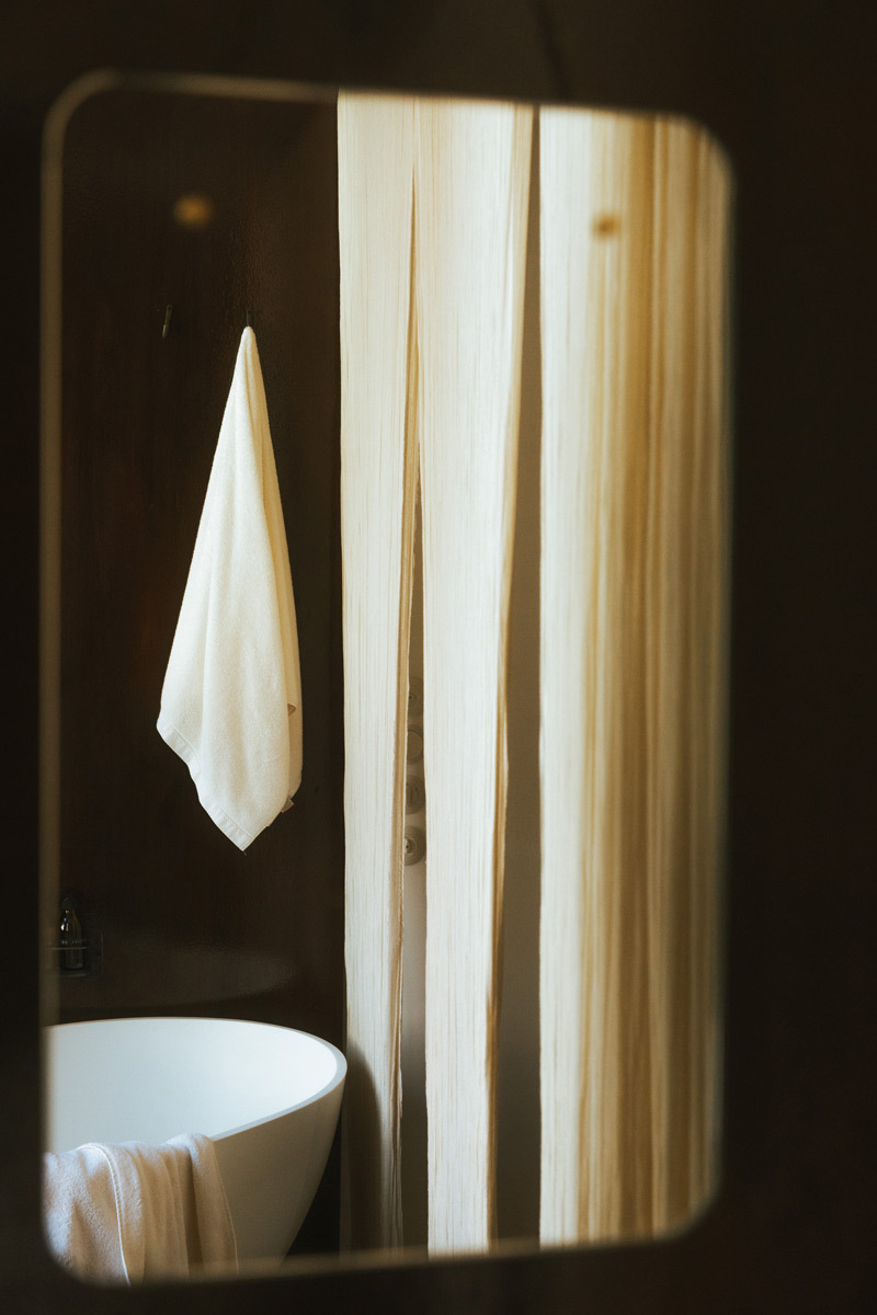 A mirror with the reflection of a bathtub and towels