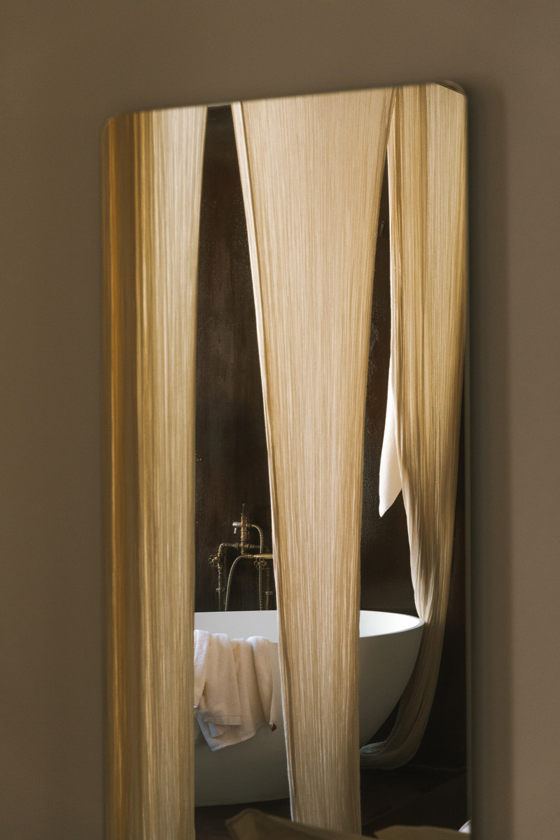 A mirror with the reflection of a bathtub and towels