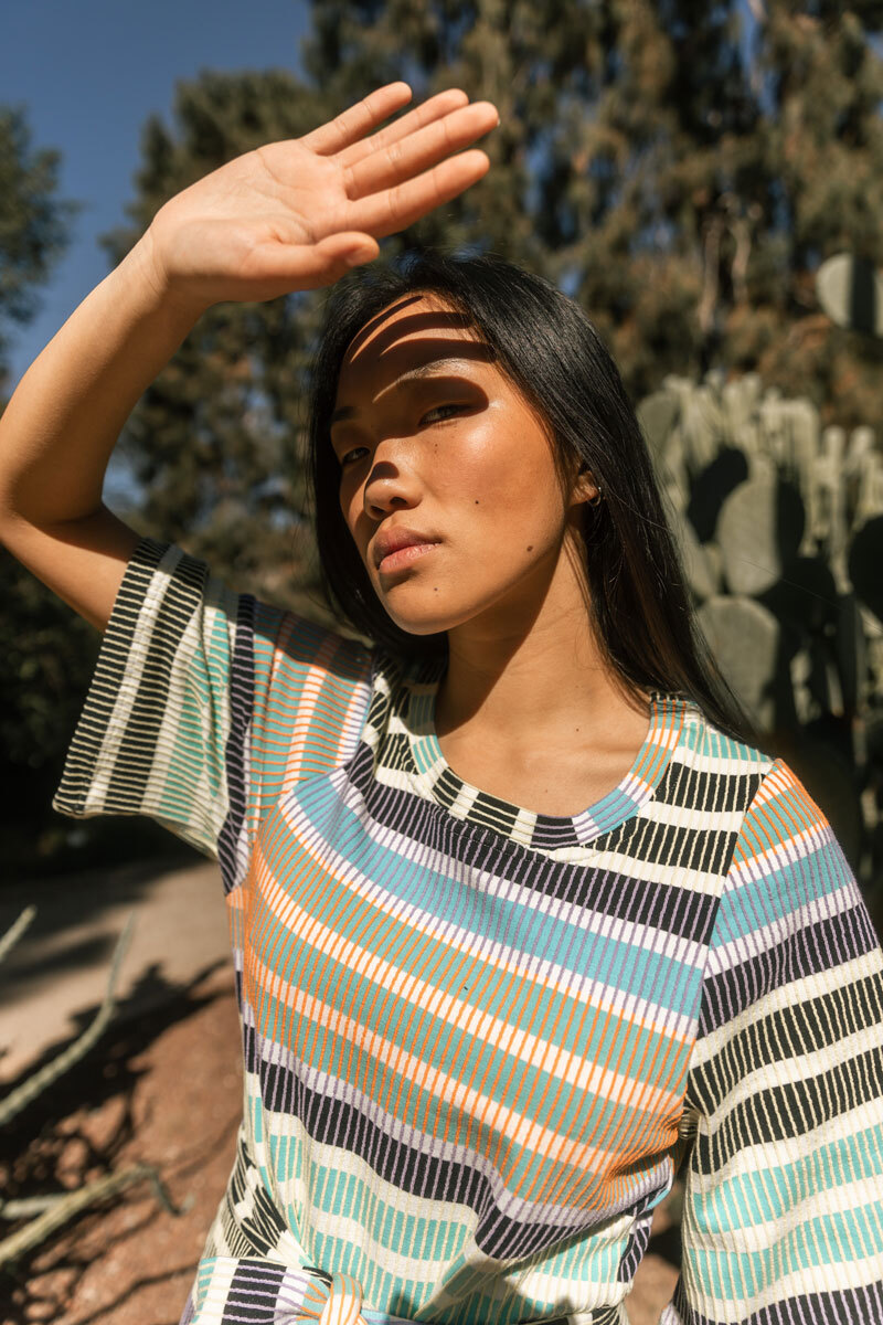 Girl holding a hand in front of her face, to protect herself from the sun.