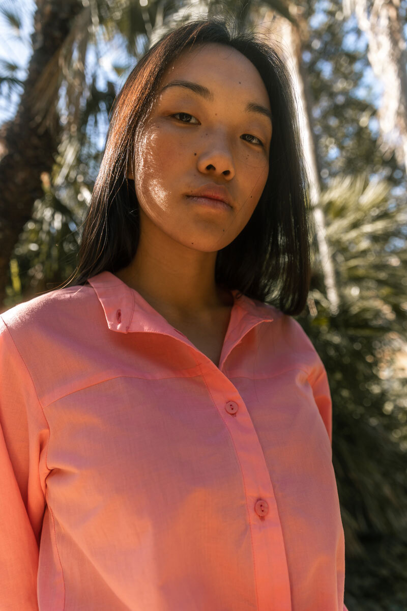 Girl standing in front of a palm tree.