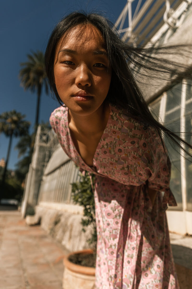 Girl looking down into the camera, wearing a flower dress.