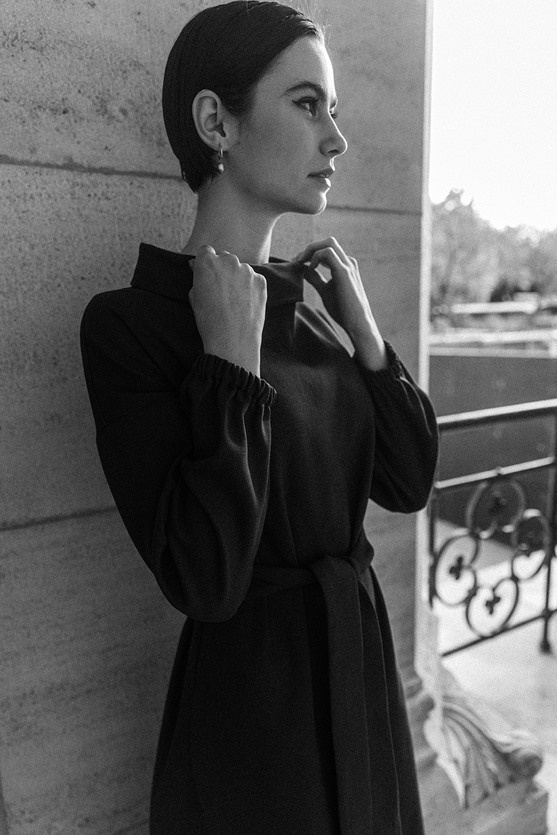 girl in black dress leaning against a wall