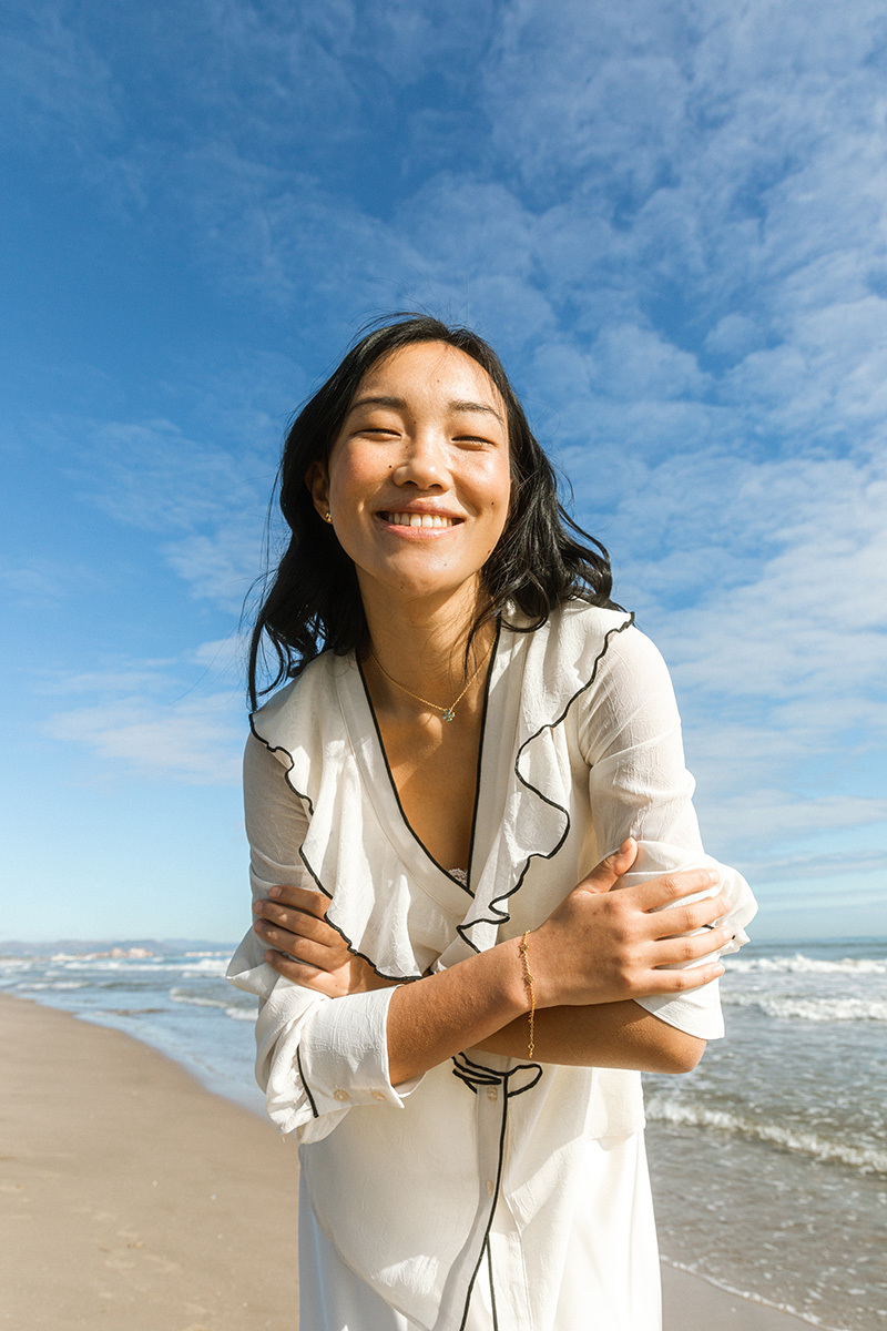 girl smiling standing in front of the ocean