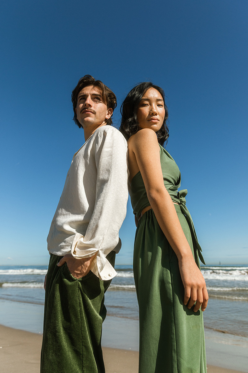 girl and boy leaning against each other, in front of the ocean