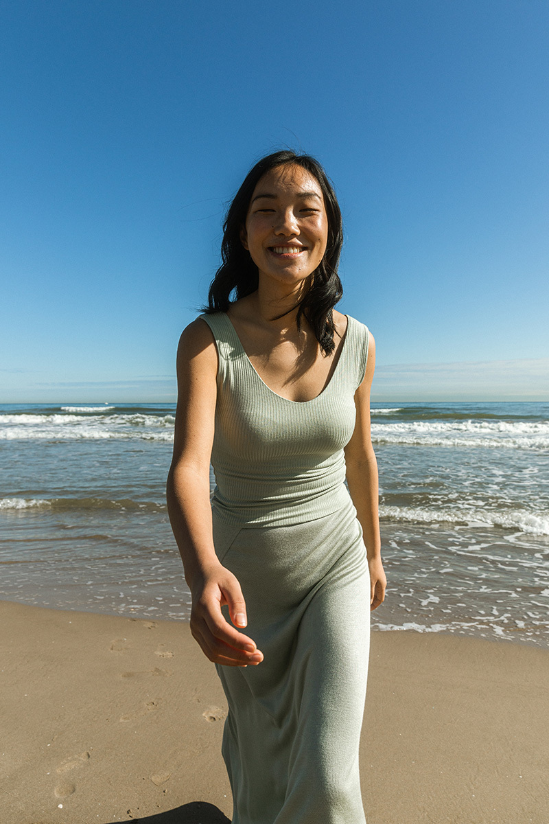 girl smiling running towards the camera in front of the ocean