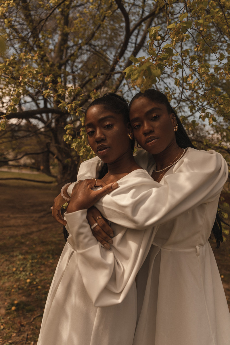 Two twins standing behind each other, hugging