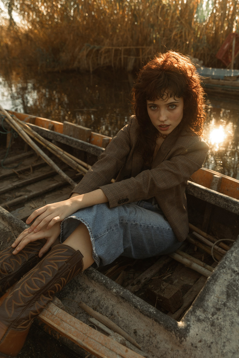 A girl sitting in an old fisherboat during sunset