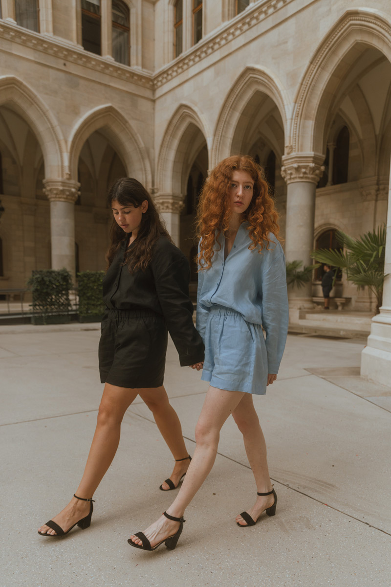 Two girls wearing hands and walking in front of historic buildings