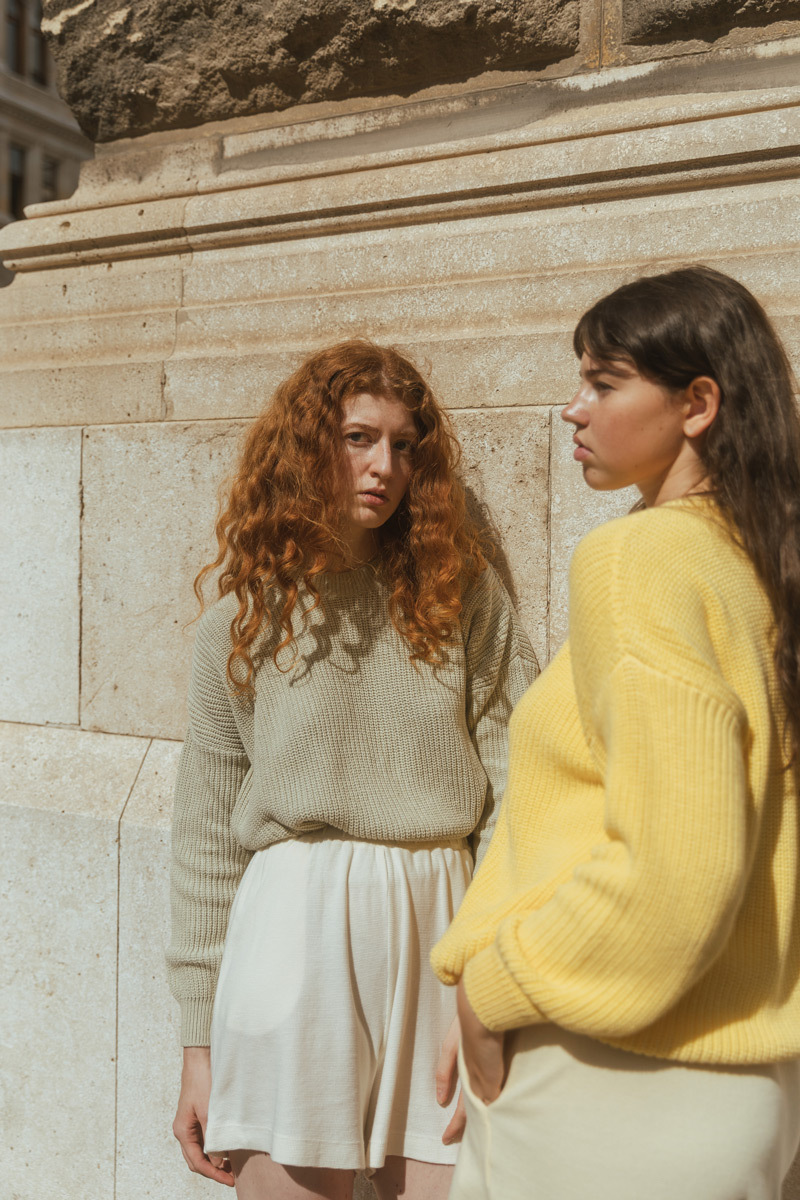 Two girls standing in the sunshine, in front of an historic building