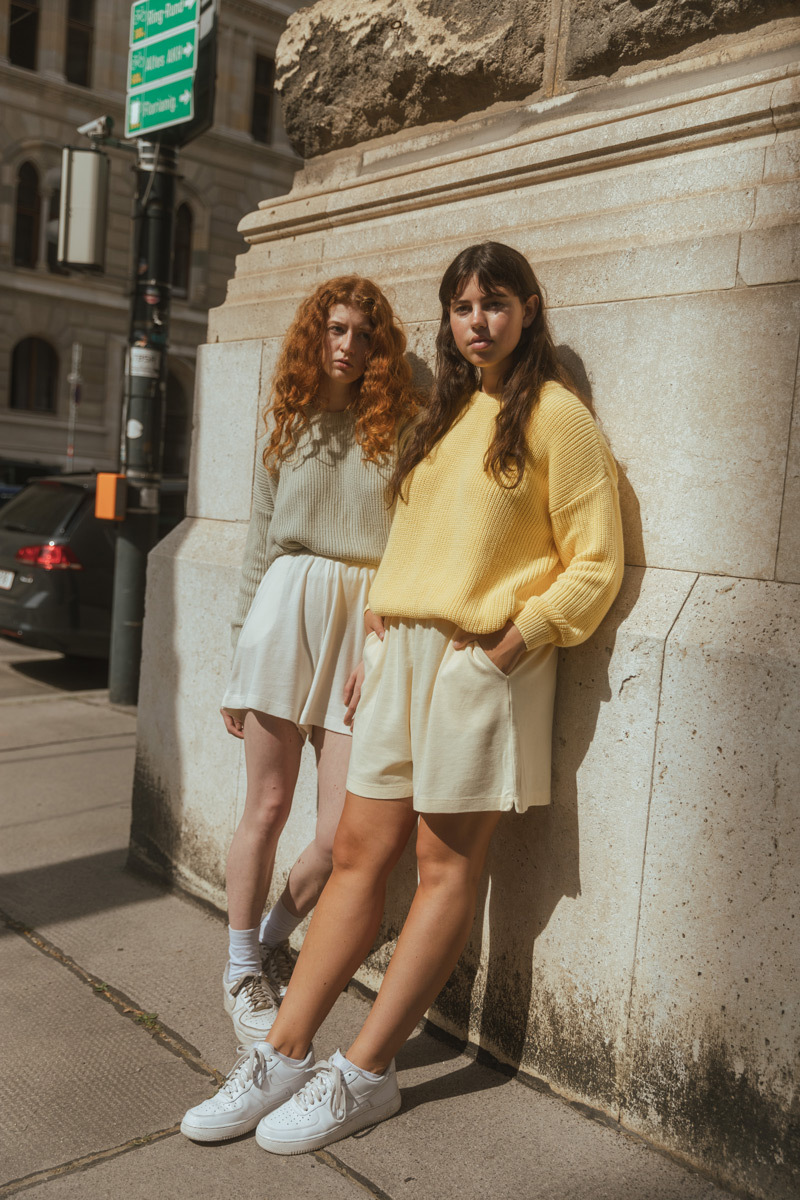 Two girls standing in front of a wall in the sun